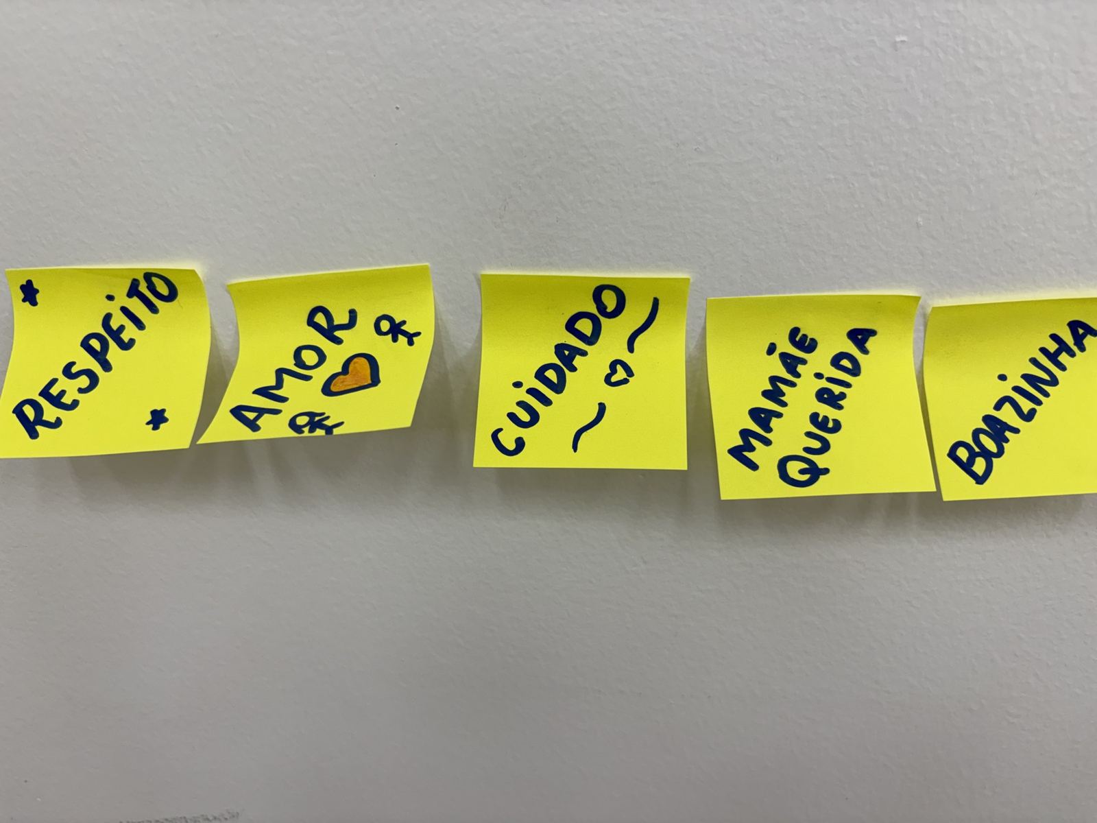 Post-its com as palavras respeito, amor, cuidado, mamãe querida e boazinha, colados na parede.