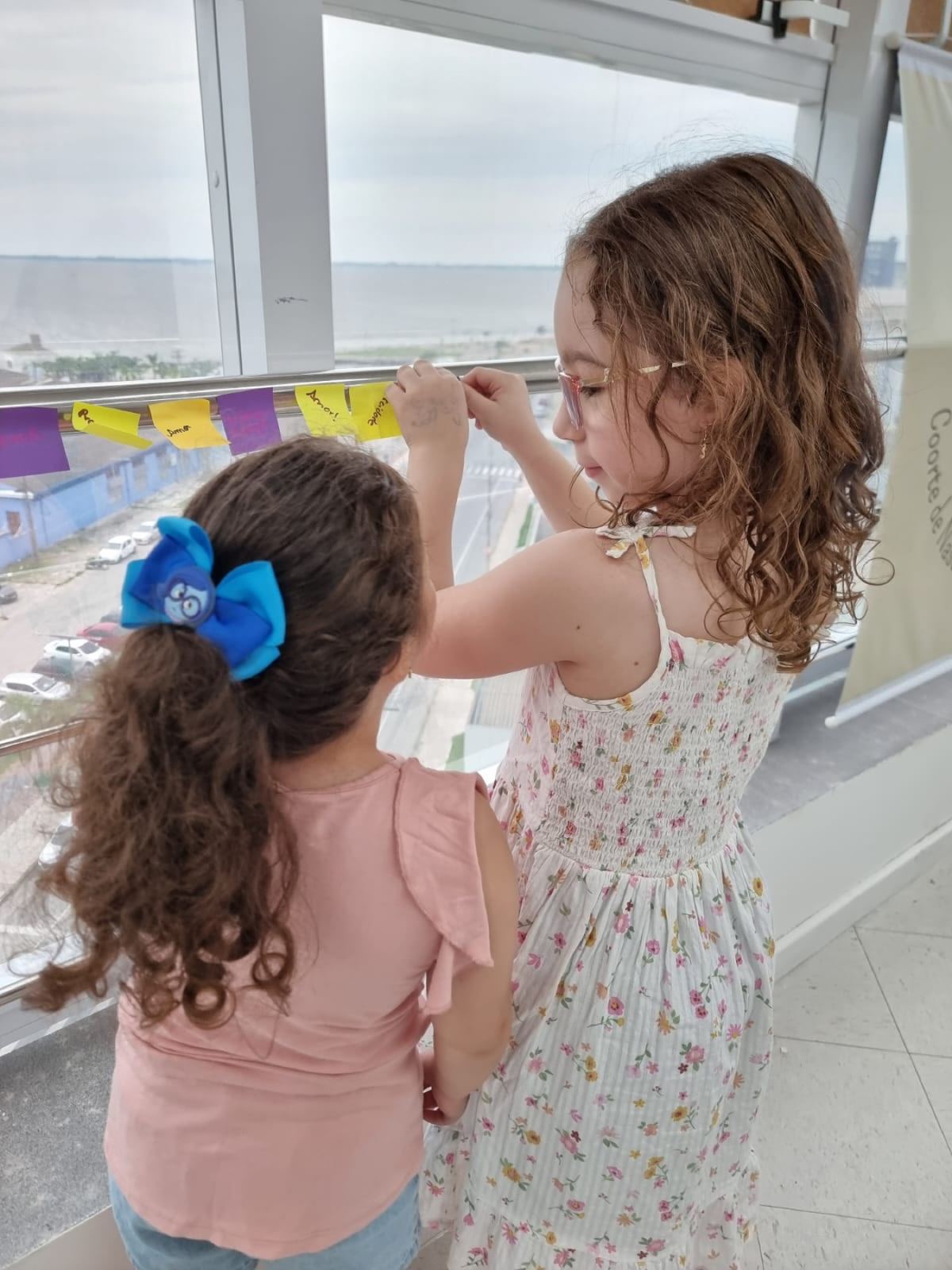 Crianças participam de atividade do GPIS com palavras afixadas em um painel.